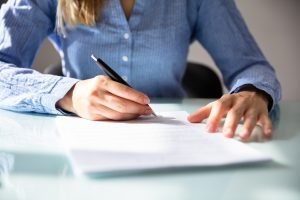 Woman sitting down writing on a piece of paper