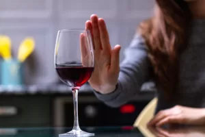Womansraising her hand to refuse a glass of wine