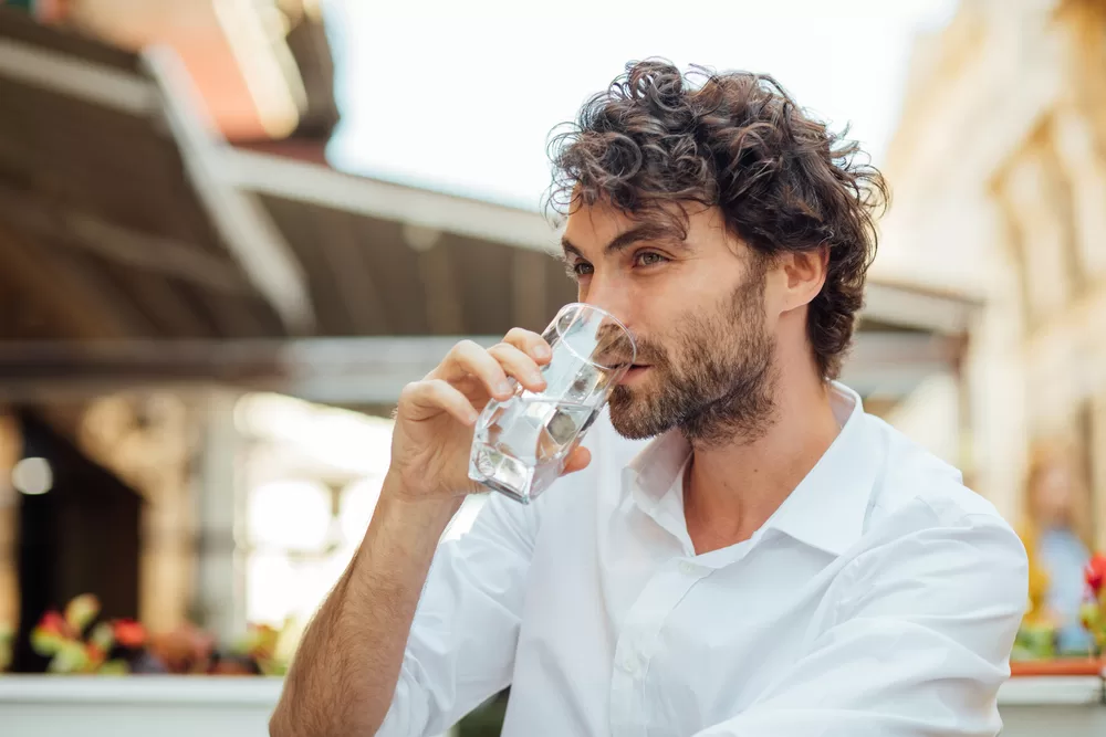 Male with curly hair drinking from a glass