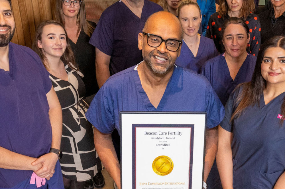 A bearded man in his 30's sits with an attractive woman in a doctor's office